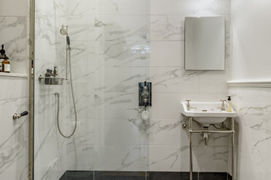 Foto di una stanza da bagno classica con doccia aperta, piastrelle bianche, piastrelle in ceramica, pareti bianche, pavimento con piastrelle a mosaico, lavabo a colonna, pavimento nero, doccia aperta e un lavabo