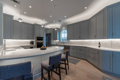 Example of a trendy light wood floor kitchen design in Houston with shaker cabinets, gray cabinets, quartz countertops, marble backsplash, stainless steel appliances and a peninsula