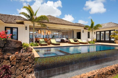 This is an example of a large beach style backyard rectangular infinity pool in Hawaii with a hot tub and natural stone pavers.