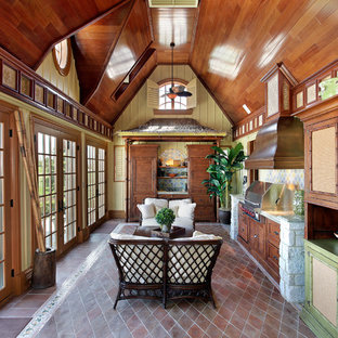 Modelo de cocina lineal, exótica, de tamaño medio, cerrada, con puertas de armario de madera oscura, encimera de granito, salpicadero multicolor, salpicadero de azulejos de piedra, suelo de baldosas de terracota, armarios con paneles empotrados y electrodomésticos de acero inoxidable