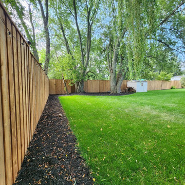 7 ft fence boards running the length of the property line under mature trees, Cl