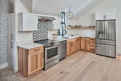 Inspiration for a mid-sized scandinavian l-shaped light wood floor, brown floor and vaulted ceiling open concept kitchen remodel in Charlotte with a single-bowl sink, shaker cabinets, medium tone wood cabinets, quartz countertops, multicolored backsplash, ceramic backsplash, stainless steel appliances and white countertops