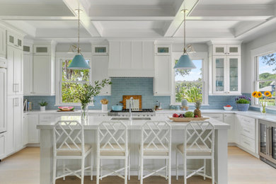 Example of a large beach style light wood floor, beige floor and coffered ceiling eat-in kitchen design in Charleston with a farmhouse sink, white cabinets, marble countertops, blue backsplash, subway tile backsplash, paneled appliances, an island and white countertops