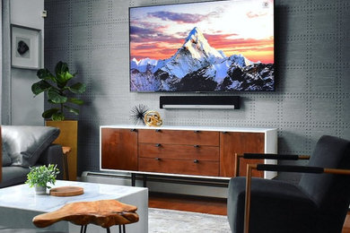 Example of a 1960s open concept medium tone wood floor, brown floor, vaulted ceiling and wallpaper living room design in New York with gray walls and a wall-mounted tv