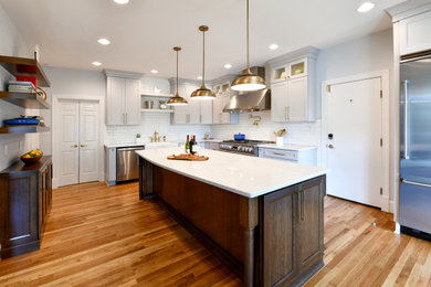 Large l-shaped medium tone wood floor and beige floor eat-in kitchen photo in DC Metro with a farmhouse sink, recessed-panel cabinets, gray cabinets, quartz countertops, white backsplash, porcelain backsplash, stainless steel appliances, an island and white countertops
