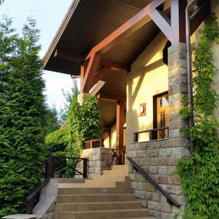 Удачное сочетание для дизайна помещения: двухэтажный фасад частного дома среднего размера желтого цвета в современном стиле с облицовкой из кирпича, двускатной крышей и черепичной крышей - самое интересное для вас