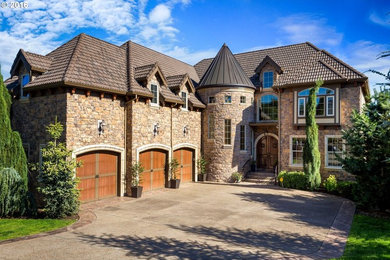 Elegant brown three-story stone house exterior photo in Portland with a hip roof and a tile roof