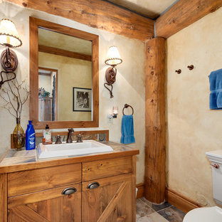Example of a mountain style gray floor bathroom design in Denver with medium tone wood cabinets, beige walls, a drop-in sink, tile countertops and brown countertops