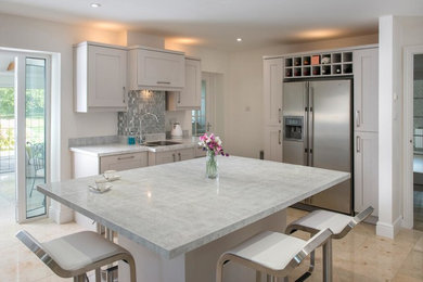 Large transitional l-shaped limestone floor and beige floor enclosed kitchen photo in Ottawa with an undermount sink, shaker cabinets, white cabinets, quartz countertops, metallic backsplash, metal backsplash, stainless steel appliances and an island