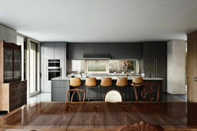 This is an example of a mid-sized contemporary single-wall eat-in kitchen in Boston with flat-panel cabinets, black cabinets, window splashback, stainless steel appliances and with island.