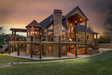 Large rustic brown two-story stucco exterior home idea in Other with a hip roof