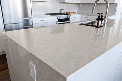 Eat-in kitchen - mid-sized contemporary eat-in kitchen idea in Vancouver with flat-panel cabinets, white cabinets, quartz countertops, quartz backsplash, stainless steel appliances and an island