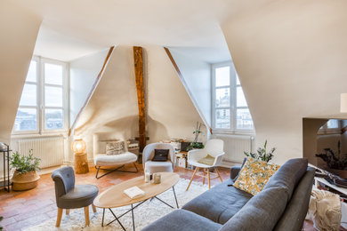 Idée de décoration pour une salle de séjour mansardée ou avec mezzanine design de taille moyenne avec un mur beige, tomettes au sol, aucune cheminée et un téléviseur dissimulé.
