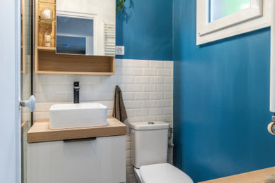 Exemple d'une petite salle de bain principale tendance en bois clair avec un placard à porte affleurante, une douche ouverte, WC à poser, un carrelage blanc, un carrelage métro, un mur bleu, carreaux de ciment au sol, un plan vasque, un plan de toilette en bois, un sol bleu, une cabine de douche à porte coulissante, un plan de toilette beige, une niche, meuble simple vasque et meuble-lavabo suspendu.