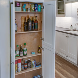 Cette photo montre une petite arrière-cuisine parallèle tendance avec un évier encastré, un placard à porte shaker, des portes de placard blanches, une crédence marron, une crédence en carreau de céramique, un électroménager en acier inoxydable, un sol en bois clair et aucun îlot.