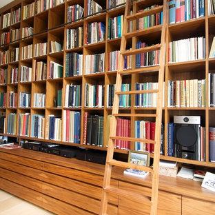 Design ideas for a large traditional home office in London with a library, beige walls, light hardwood floors, a ribbon fireplace and a plaster fireplace surround.