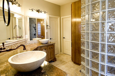 Large elegant master multicolored tile and stone tile travertine floor double shower photo in Austin with raised-panel cabinets, dark wood cabinets, beige walls, a vessel sink and granite countertops