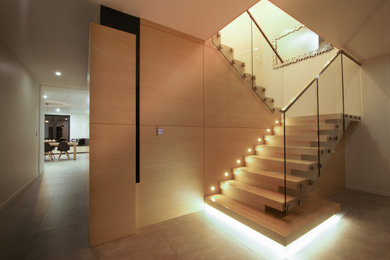 Inspiration for a mid-sized modern wood u-shaped staircase in Christchurch with wood risers and glass railing.