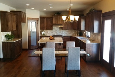 Elegant u-shaped medium tone wood floor eat-in kitchen photo in Seattle with a double-bowl sink, recessed-panel cabinets, dark wood cabinets, granite countertops, beige backsplash and an island