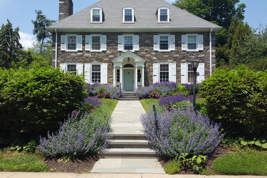 This is an example of a mid-sized traditional front yard full sun formal garden for summer in Philadelphia with a garden path and natural stone pavers.