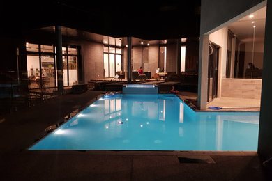 Design ideas for a large contemporary backyard l-shaped lap pool in Melbourne with a hot tub and natural stone pavers.