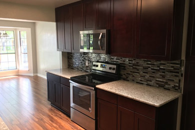 Inspiration for a mid-sized timeless galley laminate floor and brown floor eat-in kitchen remodel in Austin with an undermount sink, shaker cabinets, dark wood cabinets, granite countertops, multicolored backsplash, glass tile backsplash and stainless steel appliances