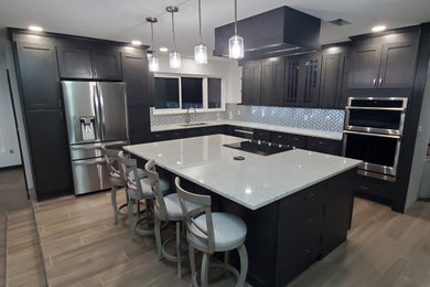 Eat-in kitchen - mid-sized contemporary l-shaped ceramic tile and brown floor eat-in kitchen idea in Orlando with an undermount sink, shaker cabinets, gray cabinets, granite countertops, white backsplash, ceramic backsplash, stainless steel appliances, an island and beige countertops