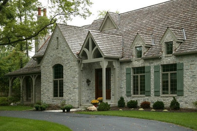 Traditional one-storey grey house exterior in Other with stone veneer.