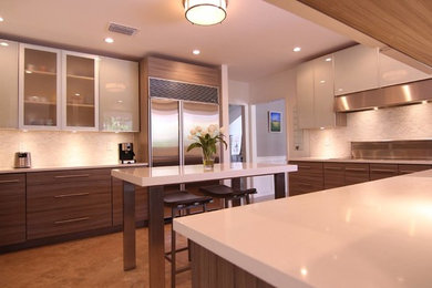 This is an example of a mid-sized contemporary u-shaped separate kitchen in Miami with flat-panel cabinets, medium wood cabinets, solid surface benchtops, white splashback, mosaic tile splashback, stainless steel appliances, porcelain floors, with island and brown floor.