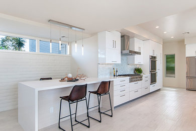 Design ideas for a large contemporary u-shaped eat-in kitchen in San Diego with an undermount sink, flat-panel cabinets, white cabinets, quartz benchtops, stainless steel appliances, blue splashback, mosaic tile splashback, a peninsula, beige floor, white benchtop and light hardwood floors.