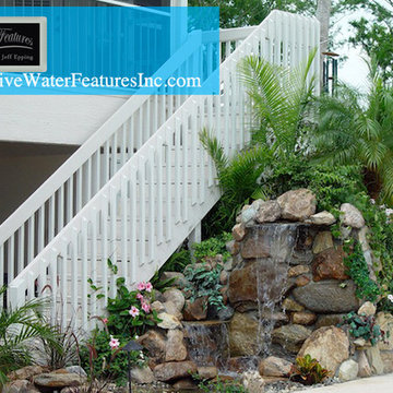 Tropical backyard room with pool waterfall, fireplace, and koi pond