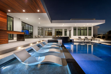 Idee per una grande piscina a sfioro infinito minimalista rettangolare dietro casa con pavimentazioni in pietra naturale