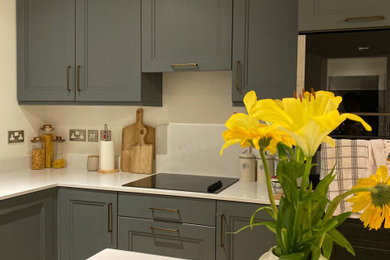 Photo of a contemporary kitchen in Dublin with shaker cabinets, grey cabinets, integrated appliances, laminate floors, an island, multi-coloured floors and multicoloured worktops.