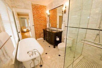 This is an example of a large transitional master bathroom in Vancouver with dark wood cabinets, a corner shower, furniture-like cabinets, a claw-foot tub, a two-piece toilet, stone tile, beige walls, marble floors and an undermount sink.