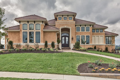 Photo of a large mediterranean two-storey stucco beige house exterior in Omaha.