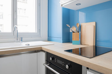 Photo of a contemporary enclosed kitchen in Paris with wood worktops and blue splashback.