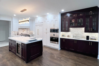 Large transitional u-shaped dark wood floor and brown floor eat-in kitchen photo in New York with a farmhouse sink, shaker cabinets, white cabinets, quartz countertops, white backsplash, stone tile backsplash, paneled appliances, an island and white countertops