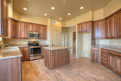 Inspiration for a large southwestern u-shaped ceramic tile and brown floor enclosed kitchen remodel in Phoenix with an undermount sink, raised-panel cabinets, medium tone wood cabinets, granite countertops, stainless steel appliances and an island