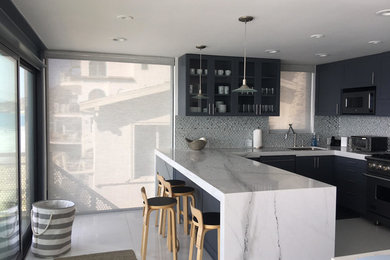 Example of a large minimalist u-shaped porcelain tile and white floor enclosed kitchen design in Los Angeles with an undermount sink, flat-panel cabinets, gray cabinets, marble countertops, gray backsplash, stone tile backsplash, stainless steel appliances and a peninsula