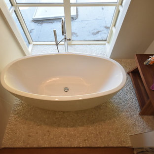 Immagine di una grande stanza da bagno padronale minimalista con ante lisce, ante in legno scuro, vasca freestanding, doccia ad angolo, WC monopezzo, piastrelle beige, piastrelle in gres porcellanato, pareti beige, pavimento con piastrelle di ciottoli, lavabo sottopiano, top in rame e pavimento beige
