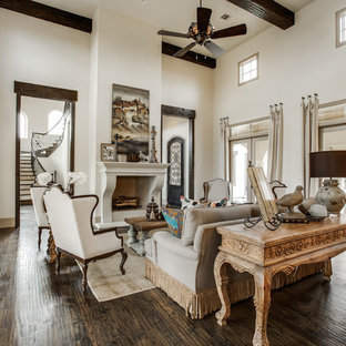 Ejemplo de salón para visitas abierto, mediterráneo, grande, con paredes beige, suelo de madera en tonos medios, chimenea tradicional, marco de chimenea de piedra y televisor retractable