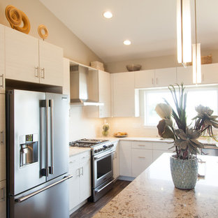 Mid-sized contemporary kitchen pantry remodeling - Example of a mid-sized trendy l-shaped laminate floor and brown floor kitchen pantry design in Cedar Rapids with a drop-in sink, flat-panel cabinets, white cabinets, quartz countertops, white backsplash, porcelain backsplash, stainless steel appliances, an island and white countertops