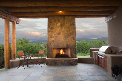 Inspiration for a mid-sized mediterranean backyard stone patio kitchen remodel in Albuquerque with a roof extension