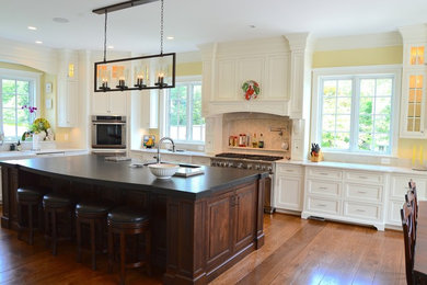 Photo of an expansive traditional l-shaped eat-in kitchen in DC Metro with a farmhouse sink, beaded inset cabinets, white cabinets, marble benchtops, beige splashback, ceramic splashback, panelled appliances, medium hardwood floors and with island.