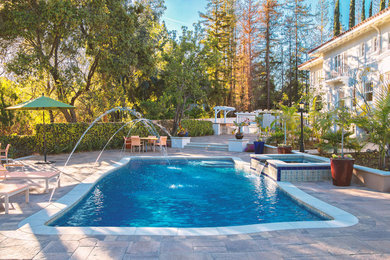Photo of a large tropical backyard rectangular lap pool in Los Angeles with a hot tub and brick pavers.