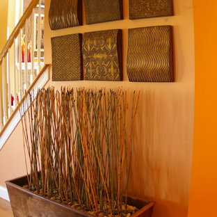 Inredning av en eklektisk entré, med orange väggar och mellanmörkt trägolv