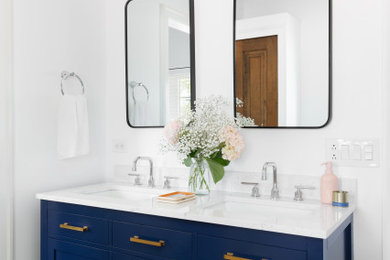 ニューヨークにある低価格の中くらいなトランジショナルスタイルのおしゃれな浴室 (青いキャビネット、洗面台2つ、独立型洗面台) の写真