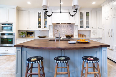 Eat-in kitchen - mid-sized traditional l-shaped travertine floor eat-in kitchen idea in Houston with a single-bowl sink, recessed-panel cabinets, white cabinets, wood countertops, blue backsplash, terra-cotta backsplash, paneled appliances and an island