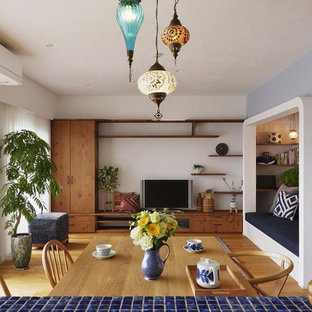 Mediterranean open plan living room with multi-coloured walls, medium hardwood flooring, a freestanding tv and brown floors.