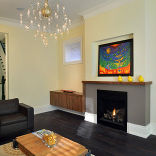 Inredning av ett modernt mellanstort separat vardagsrum, med gula väggar, ett finrum, mörkt trägolv, en standard öppen spis och en spiselkrans i gips